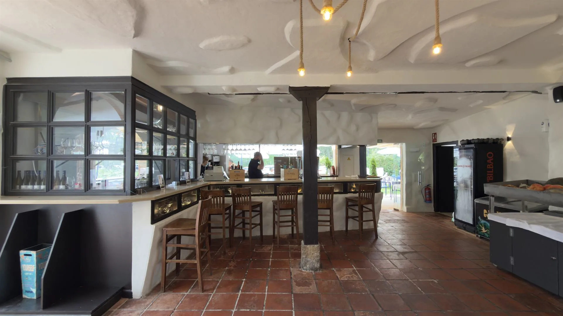 Barra del restaurante con lámparas de cuerda y suelo de barro